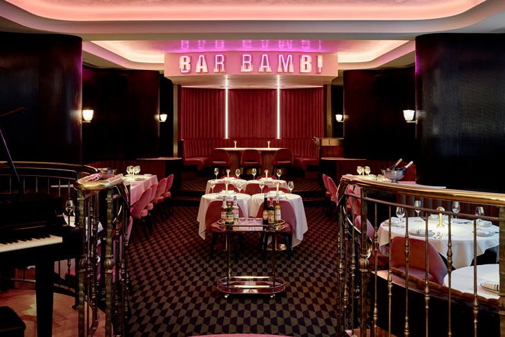The dining room at Bar Bambi, with cherry red carpet, pink velvet chairs and a pink neon sign that reads